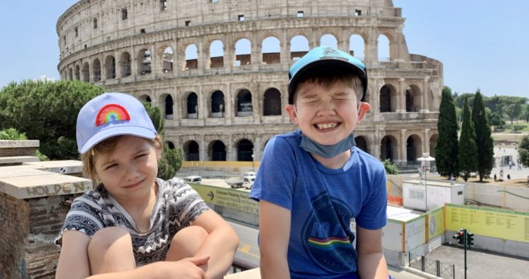 Two kids smiling in front of the Roman Coliseum